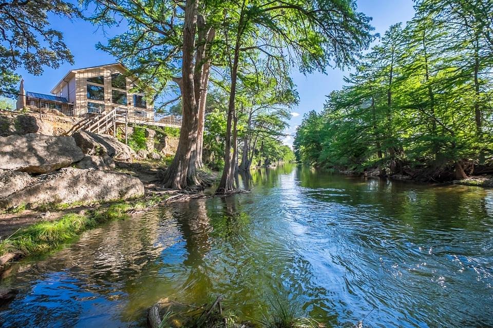 Rio Frio cercado por ciprestes no outono, com uma pessoa e um cachorro à margem